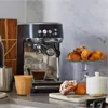 A kitchen counter scene featuring an espresso machine with coffee and pastries. Produktbild-Vorschau
