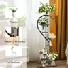 A multi-tiered plant stand with flowers and decorative items, placed in a room with curtains and furniture. Anteprima dell’immagine prodotto