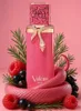 A pink perfume bottle with a gold snake wrapped around it, surrounded by raspberries, blackcurrants, and rosemary sprigs, on a pink background. Voir les images du produit