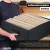 A person is holding a black storage box filled with folded beige items, likely clothes or towels. Náhľad obrázku produktu