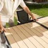 A person is adjusting an extendable outdoor table on a patio. Produktbild-Vorschau