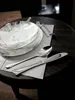 A close-up shot of a dinnerware set and cutlery on a dark wooden table. Anteprima dell’immagine prodotto