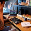 A person is using a DJ controller and laptop in a room. Produktbild-Vorschau