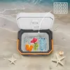 An open cooler box filled with ice, drinks, and fruit, placed on a sandy beach with the ocean in the background. Náhľad obrázku produktu