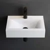 A white ceramic sink with a black faucet against a dark gray wall. Produktbild-Vorschau