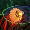 A lit-up badminton shuttlecock rests on a badminton racket in the grass. Produktbild-Vorschau