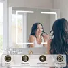 A woman applying makeup in front of a lit bathroom mirror cabinet. Produktbild-Vorschau