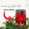 A red glass candle holder with a decorative lid sits amongst green ivy leaves, with a red arrow pointing to the candle holder and text overlays. Produktbild-Vorschau