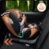 A baby is sitting in a car seat in the back seat of a car. Produktbild-Vorschau
