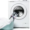 A plush dog toy peeking out of a laundry basket next to a washing machine. Voir les images du produit