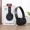 A black pair of wireless headphones and their packaging are displayed on a wooden surface. Produktbild-Vorschau