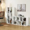 A white bookshelf unit is shown in a room with wooden flooring and a wall with two framed mountain pictures. Podgląd zdjęcia produktu