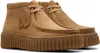 A pair of tan Clarks Wallabee boots with a thick, ridged sole, shown from a slightly angled front view against a white background. Voir les images du produit