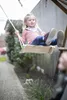 A young girl is swinging on a wooden swing in an outdoor setting. Produktbild-Vorschau