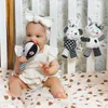 A baby sitting in a crib, playing with a rattle. Produktbild-Vorschau