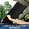 Schwarze automatisch ausziehbare Sonnenblende wird von einer Hand an einer Windschutzscheibe angebracht, mit Bäumen im Hintergrund sichtbar Voir les images du produit