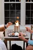 People making s'mores around a portable fire pit on a table. Produktbild-Vorschau