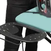 A close-up view of an ironing board with an iron on it, and a person's legs in black pants visible in the background. Produktbild-Vorschau