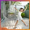 A young girl is jumping on a wooden deck next to a hanging chair. Voir les images du produit