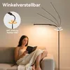 A woman is reading a book on a couch, illuminated by a floor lamp. Produktbild-Vorschau