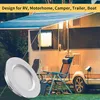 A close-up of a circular LED light fixture in the foreground, with a camper van and outdoor chairs in the background. Náhľad obrázku produktu