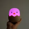 A hand holds a cute chick-shaped night light that is glowing pink. Produktbild-Vorschau