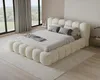 A bedroom scene with a large, plush bed as the focal point, set against a backdrop of large windows with a view of greenery. Voir les images du produit