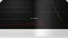 A close-up shot of a black Bosch induction cooktop with red digital displays. Podgląd zdjęcia produktu
