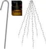 A silver ground stake and a string of warm white LED lights shaped like a tree are shown against a white background. A small inset image shows the lights illuminated in a garden setting. Náhled obrázku produktu