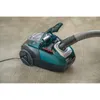 A teal and black canister vacuum cleaner with its lid open, sitting on a textured carpet. Produktbild-Vorschau