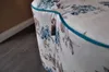 A close-up view of a floral patterned ottoman with turquoise piping. Produktbild-Vorschau