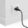 A black power cord plugged into a white electrical outlet on a white wall. Produktbild-Vorschau