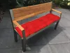 A red cushion on a modern garden bench placed on a tiled patio. Produktbild-Vorschau