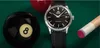 A watch is placed on a green pool table next to a black 8-ball and a pool cue. Produktbild-Vorschau