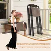 A woman is carrying a folded bar stool on a porch, with other folded bar stools stacked nearby. Produktbild-Vorschau