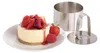 A small cheesecake topped with strawberries and raspberries sits on a white plate, next to a stainless steel dessert ring mold. Produktbild-Vorschau