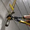 A hand using a pair of pliers to adjust a pipe fitting. Voir les images du produit