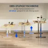 Three adjustable standing desks are shown at different heights in a room with a light-colored wall and wooden floor. Anteprima dell’immagine prodotto