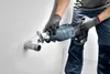 A person wearing gloves is using a Festool reciprocating saw to cut a pipe protruding from a wall. Voir les images du produit