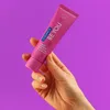 A hand holding a tube of toothpaste against a purple background. Anteprima dell’immagine prodotto