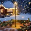 A decorative spiral Christmas tree with gold LED lights and a star on top, placed on a wooden table with pine branches and pinecones, in a snowy outdoor setting with a house in the background. Voir les images du produit