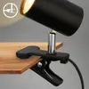 A black desk lamp with a clamp attached to a wooden surface. Náhled obrázku produktu