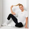 A woman is sitting in a white corner, holding her ponytail. Produktbild-Vorschau