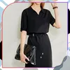 A woman wearing a black dress and holding a black purse. Náhled obrázku produktu