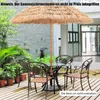 An outdoor patio setting with a thatched umbrella and a table with chairs. Anteprima dell’immagine prodotto