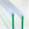 Close-up view of two transparent shower door seals attached to green glass panels. Podgląd zdjęcia produktu