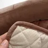 A close-up of a hand holding the corner of a quilted pet bed cover, showing the stitching and non-slip dots on the underside. Náhled obrázku produktu