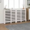 A white radiator cover is placed in front of a window, with decorative items on top. Náhľad obrázku produktu