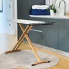 A wooden ironing board is set up on a circular rug in a laundry room or kitchen area. Produktbild-Vorschau