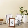 Three picture frames with deer illustrations are displayed on a wooden surface, with a vase and greenery in the background. Produktbild-Vorschau